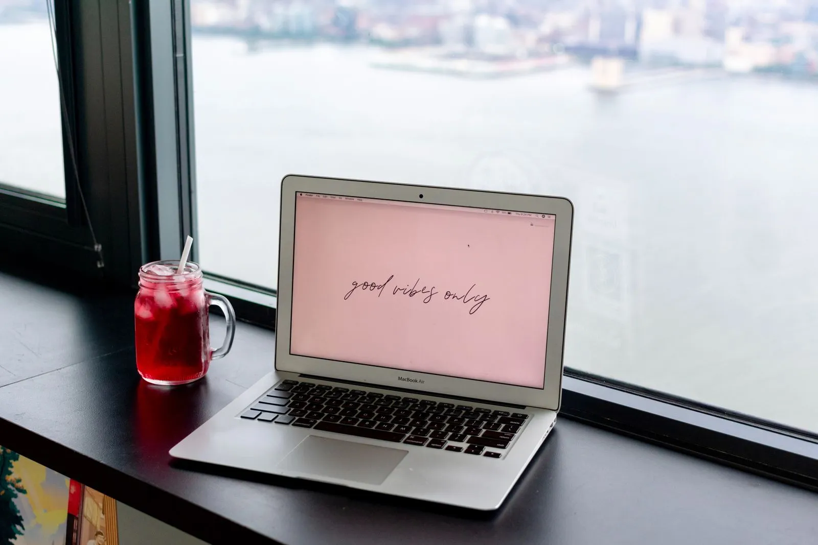 From above of netbook with inscription on screen near glass of beverage with ice near window in cafe
